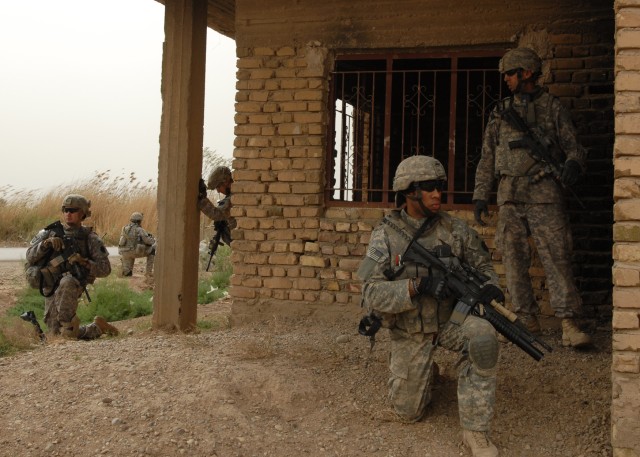 CAMP TAJI, Iraq - Sgt. Oshea Washington (kneeling, right) of Easton, Pa., a Soldier with Company C, 1st Battalion, 111th Infantry Regiment, 56th Stryker Brigade Combat Team, takes up a position at the corner of a building to pull security. The Soldie...