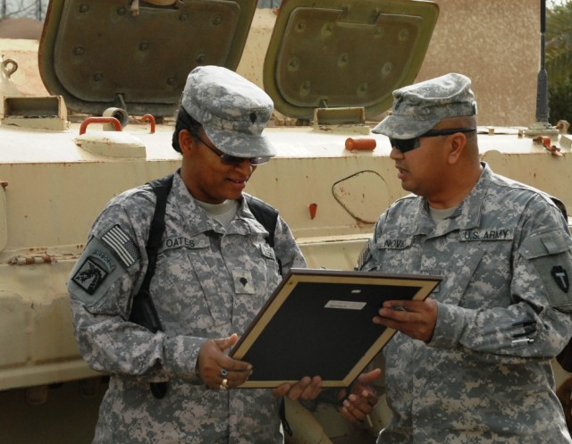 BAGHDAD - Spc. Verna Oates (left), from Texarkana, Texas, serving with Headquarters and Headquarters Company, 56th Infantry Brigade Combat Team, 36th Infantry Division, Multi-National Division-Baghdad, receives a framed copy of the Non-Commissioned O...