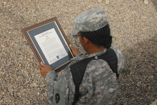 BAGHDAD - Spc. Verna Oates, from Texarkana, Texas, serving with Headquarters and Headquarters Company, 56th Infantry Brigade Combat Team, 36th Infantry Division, Multi-National Division-Baghdad, reads a framed copy of the Non-Commissioned Officer's C...