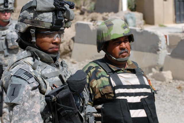 BAGHDAD - Philidelphia native, Spc. Tymara Burnley (left), a medical logistics specialist with 299th Brigade Support Battalion, stands guard with an Iraqi Army soldier during a public works sub-station transfer ceremony at Yarmouk in the Mansour dist...