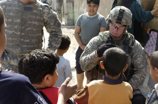 BAGHDAD - Spc. John Young, a native of Durham, N. C., assigned to Troop C, 5th Squadron, 73rd Cavalry Regiment, greets some Iraqi children during a combined foot patrol in Baghdad's Rusafa district March 7 with National Police officers from the...