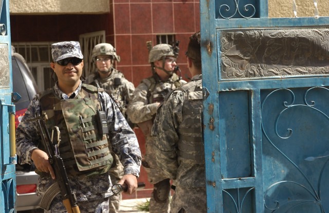 BAGHDAD - National Police Officers assigned to the 3rd Battalion, 8th NP Brigade, 2nd NP Division and paratroopers assigned to Troop C, 5th Squadron, 73rd Cavalry Regiment, walk out of a residence after inspecting it during a Iraqi-led clearance...