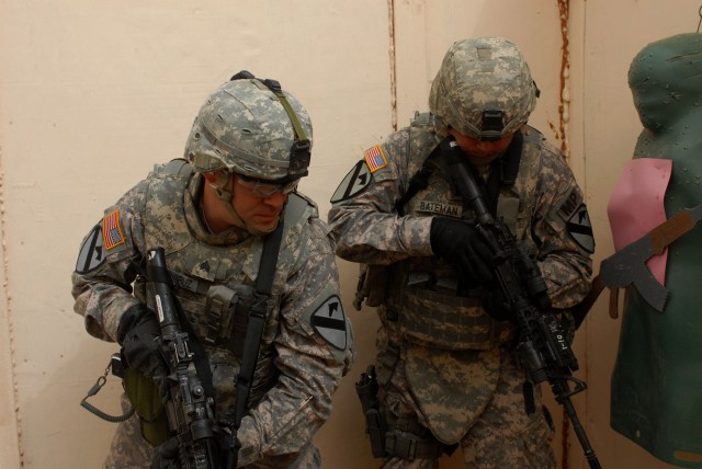 CAMP BUERHING, Kuwait - Nawasota, Texas native Sgt. Hiram Delacruz (left), a squad leader from 1st Brigade Special Troops Battalion, 1st Brigade Combat Team, 1st Cavalry Division, checks an "insurgent" after clearing the room while Buffalo, N.Y. nati...