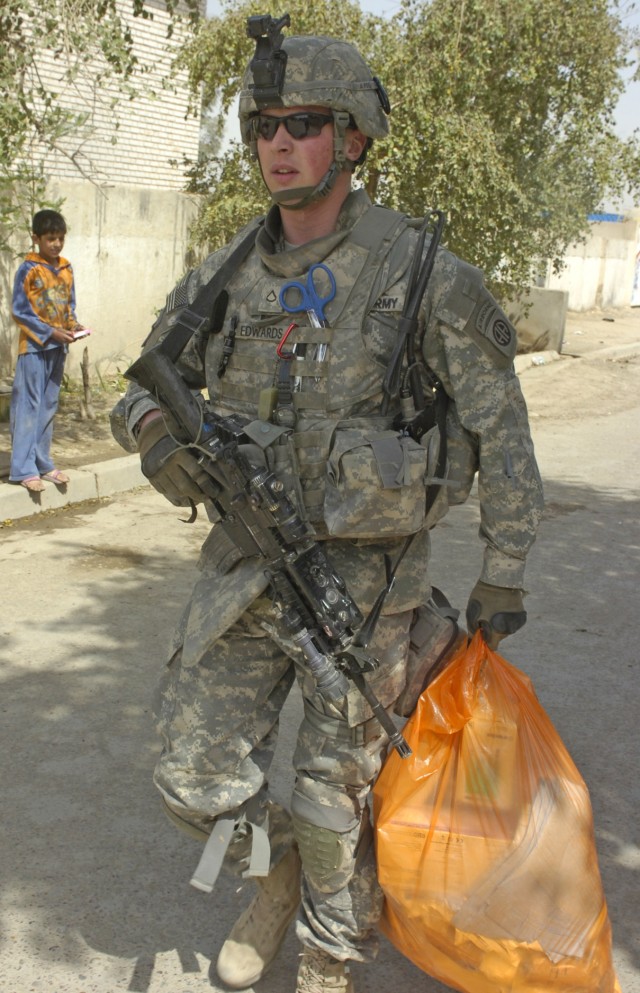 BAGHDAD - Pfc. Robert Edwards, a medic assigned to the Military Police platoon, Brigade Special Troops Battalion, 3rd Brigade Combat Team, 82nd Airborne Division, Multi-National Division-Baghdad, carries a bag of medical supplies to donate to a nearb...