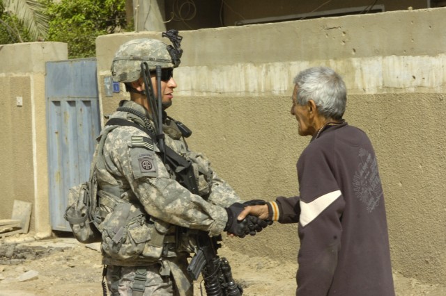 BAGHDAD - Sgt. Javier Santiago, a team leader assigned to the Military Police platoon, Brigade Special Troops Battalion, 3rd Brigade Combat Team, 82nd Airborne Division, Multi-National Division-Baghdad, greets a local resident during a foot patrol in...