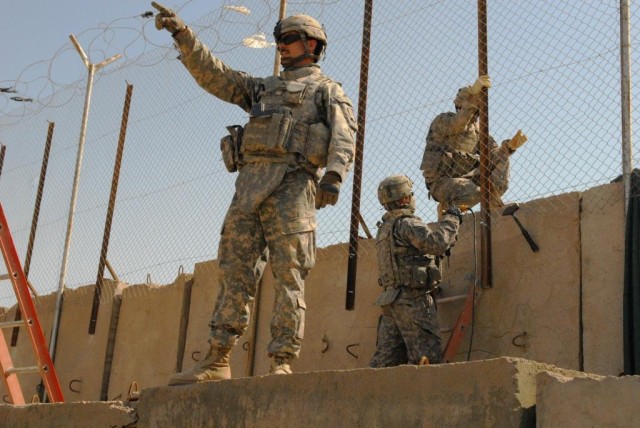 BAGHDAD - Sgt. Michael Sones, from Dallas, points out the construction progress while two of his fellow Soldiers from the 46th Engineer Battalion, 225th Engineer Brigade continue working on a perimeter screen March 17.  For the past week, Soldiers...