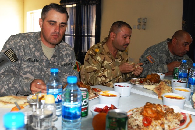 BAGHDAD - Maj. Jim Mullin (left), team chief, Team Weasel, 6th IA Div. MiTT, eats a traditional meal with his Iraqi counterparts at JSS Salam. "We live with our guys, sometimes we eat with them, we go on missions with them," he said. "If this base ha...