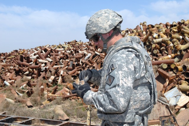 CAMP TAJI, Iraq - Sgt. Robert Solesbee, assigned to 710th Explosive Ordnance Disposal Company, 3rd Ordnance Battalion, 71st Ordnance Group and a native of Corona, Calif., examines fuses from unexploded ordnance found among piles of scrap metal to...