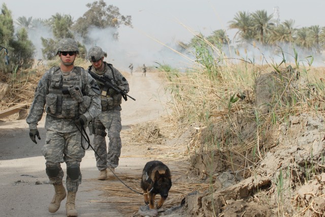 Sgt. Christopher Jasper (left), a kennel master from Everett, Wash., and his German Sheppard, Uwe, assigned to the Provost Marshall's Office, Camp Liberty K-9 section, 1st Cavalry Division, look for unexploded ordnance, weapon caches and improvised e...