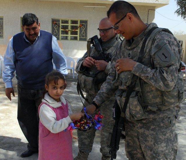 BAGHDAD - A student of Al-Khaladeen School gives a piece of candy to Sgt.1st. Class Sesilio Astorga of Company A, 1st Combined Arms Battalion, 63rd Armor Regiment, who hails from Rexburg, Idaho, during a ribbon cutting ceremony held to celebrate the ...