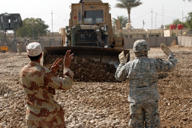 A 6th Iraqi Army engineer Soldier (left) learns important hand and arm signals from Sgt. Augustine Deluna, a heavy construction equipment operator, assigned to the 277th Engineer Company, 46th En. Battalion, 225th En. Brigade. The U.S. engineers taug...