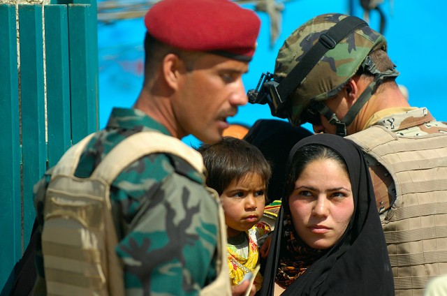 BAGHDAD-Mother and child wait outside the front gate entrance to the New Iraq School March 19. All comers were examined by Coalition medical personnel, and given humanitarian supplies such as non perishable food items, tooth brushes, and short...