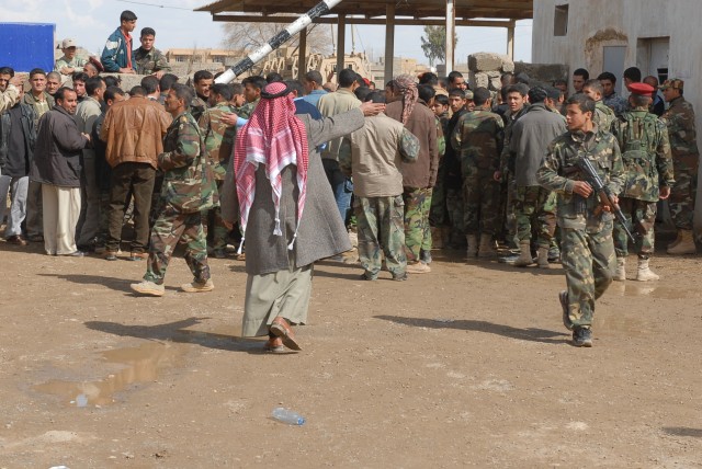 A shaykh with the Sons of Iraq directs the crowd as they wait to receive payment in the city of Sudayra in the province of Kirkuk, Iraq, March 2. This is the last payment that Coalition forces will be making to the SoI. Next month, the Government...