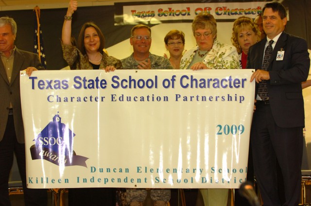 Members of the Killeen Independent School District and III Corps and Fort Hood deputy commander, Brig. Gen. James M. McDonald, hold up the banner that was awarded to Duncan Elementary School for winning the Texas State School of Character award,...