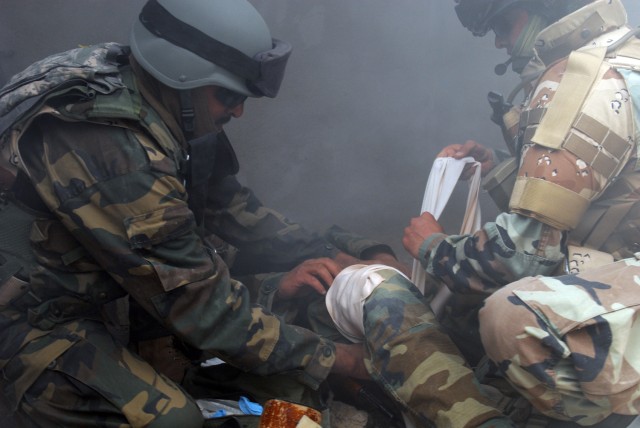 BAGHDAD - Soldiers of 6th Iraqi Army Division work quickly to treat a simulated casualty March 25, as the room they are in fills up with smoke during combat life saver training at Joint Security Station Salam. Visibility quickly became nil as smoke f...
