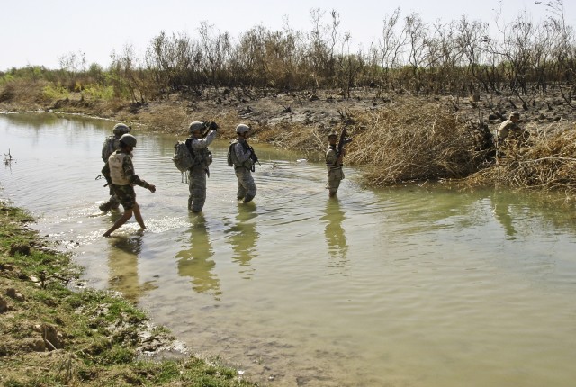 An Iraqi Soldier secures the far side of a shallow stream while Soldiers from Battery A, 5th Bn., 82nd Field Artillery Regiment, 4th Brigade Combat Team, 1st Cavalry Division, and 2nd Battalion, 41st Iraqi Army Brigade, cross the stream near...