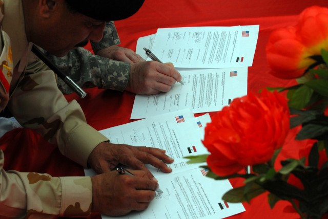 BAGHDAD - Maj. Gen. Hussein Jassim, executive chief of staff of the Iraqi Army for training and Aurora, Ill. native, Maj. Gen. Daniel Bolger, commander of Multi-National Division - Baghdad, sign the transfer documents at the Forward Operating Base Ru...