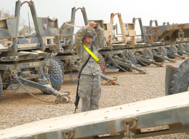 CAMP LIBERTY, Iraq - Spc. Laura Boxley, a truck driver with the 154th Transportation Co. from Belton, Mo., 553rd CSSB, 10th Sust. Bde., 3rd ESC gives hand and arm signals to ground guide a flat rack from a Pallatized Load System truck in the motor...