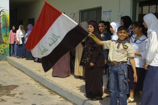 BAGHDAD -An Iraqi boy waves an Iraqi flag during a distribution event April 1 in the area of Sumer al-Ghadier, located in the 9 Nissan district of eastern Baghdad. District and National Police officials handed out clothes and school supplies to...