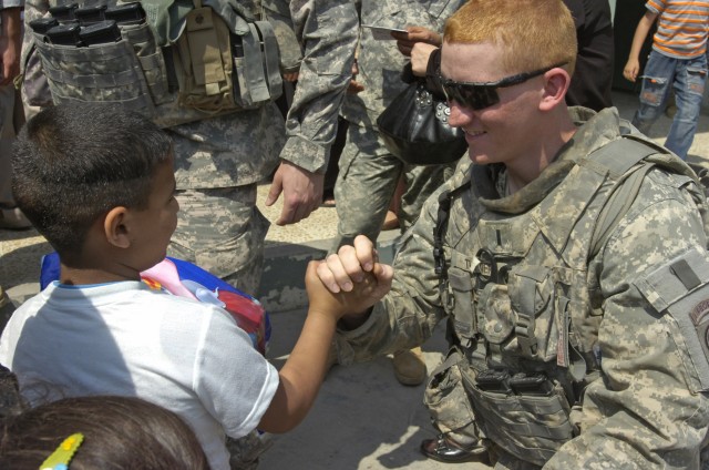 BAGHDAD - 1st Lt. Phillip Turner, of Elizabethtown, Ky., greets an Iraqi child during a distribution event April 1 in the area of Sumer al-Ghadier, located in the 9 Nissan district of eastern Baghdad. Turner and Paratroopers assigned to the...