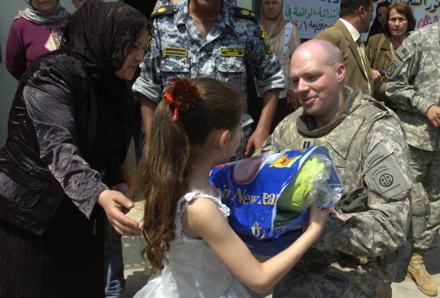BAGHDAD -Capt. Clay White, commander of Company C, 2nd Battalion, 505th Parachute Infantry Regiment, 3rd Brigade Combat Team, 82nd Airborne Division, hands an Iraqi girl clothes and school supplies during a distribution event in the area of Sumer...