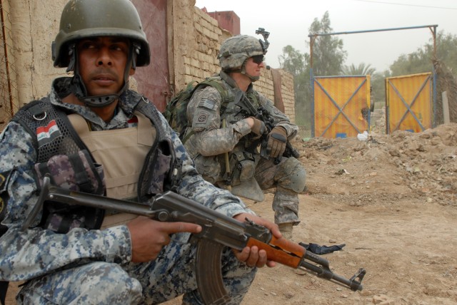 BAGHDAD - An Iraqi National Policeman and Spc. Michael Ingles, a cannon crewmember from Royce City, Texas, assigned Battery B, 1st Battalion, 319th Airborne Field Artillery Regiment, take a break from searching houses here March 30 during...