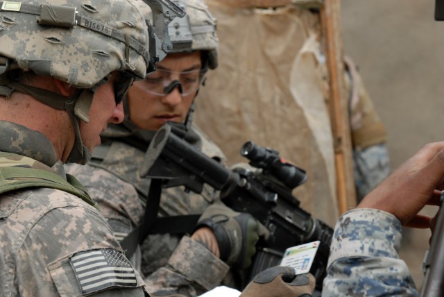 BAGHDAD - Spc. Michael Ingles (forground), a native of Royce City, Texas and Spc. Martin Aguilar, from Downey, Calif., both cannon crewmembers assigned to Battery B, 1st Battalion, 319th Airborne Field Artillery Regiment, check a man's...