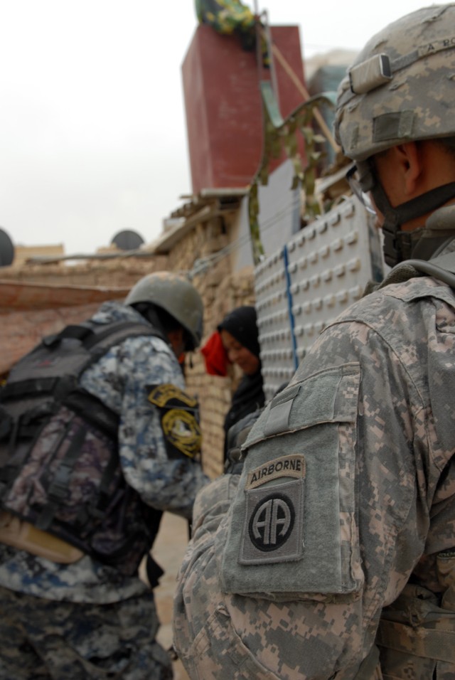 BAGHDAD - Spc. Martin Aguilar, a cannon crewmember from Downey, Calif., assigned to Battery B, 1st Battalion, 319th Airborne Field Artillery Regiment, checks a cabinet in a kitchen to search for weapons or explosives during a cordon and sweep...