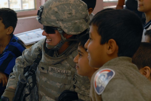 BAGHDAD - Spc. Melissa Mancillas, from Lyndonville, Vt., an MP with the 978th MP Company, 93rd MP Battalion, mingles with Iraqi children during a humanitarian mission at al-Aldara Primary School March 31. The 978th, along with Iraqi Police,...