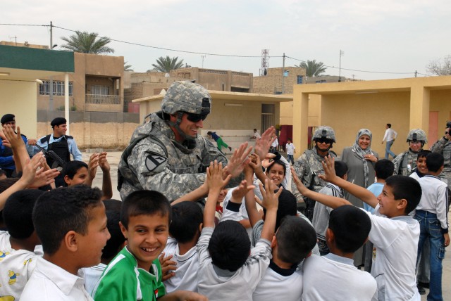 BAGHDAD - Second Lt. Patrick Koerwitz, platoon leader, 978th Military Police Company, 93rd MP Battalion, high-fives Iraqi children at al-Aldara Primary School. "We're trying to do something good for the community and we're getting the (Iraqi...