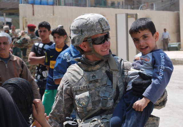 BAGHDAD - Staff Sgt. Arnold Zarza, of Mibui, Fla., carries an Iraqi boy during a combined humanitarian mission April 1 in the al-Fadhil neighborhood of eastern Baghdad. Paratroopers assigned to 5th Squadron, 73rd Cavalry Regiment, 3rd Brigade...
