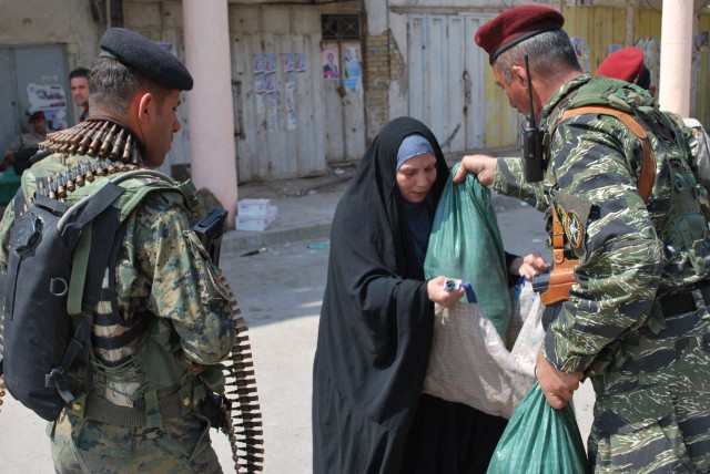 BAGHDAD - Iraqi Army soldiers hand a bag of food to an Iraqi woman during a combined humanitarian mission April 1 in the al-Fadhil neighborhood of eastern Baghdad. Paratroopers assigned to 5th Squadron, 73rd Cavalry Regiment, 3rd Brigade Combat...