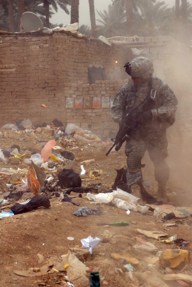 BAGHDAD - Staff Sgt. Roberto Moreno, a cannon crewmember, assigned to Battery B, 1st Battalion, 319th Airborne Field Artillery Regiment, patrols a dusty and trash-filled street in Zafaraniyah, Iraq, March 30. Moreno and his fellow paratroopers...