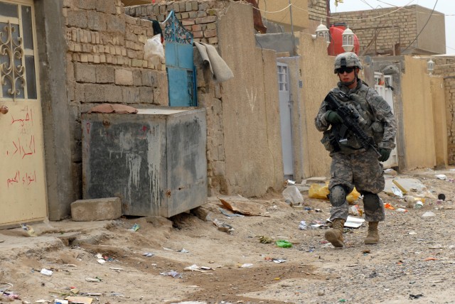 BAGHDAD - Spc. Jeremy Bowers, a medic assigned to Battery B, 1st Battalion, 319th Airborne Field Artillery Regiment, walks down an alleyway in a neighborhood in Zafaraniyah, Iraq, March 30, during a joint operation. The operation lasted for over...