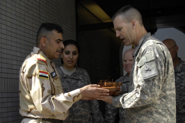 BAGHDAD - Staff Maj. Gen. Qassim Jassem Nazal, an armor officer and commander, 9th Iraqi Army Division, (left) accepts a gift of a model mahogany M1-A1 Abrams Main Battle Tank from Col. Pat White, also an armor officer and commander, 2nd Brigade...