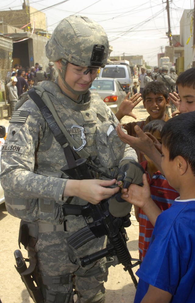 SHAWRA WA UM JIDIR, Iraq - Spc. Nicole Willson, of Hillsdale, Mich., places an adhesive bandage on an Iraqi boy's finger during a foot patrol April 4 inside a market in the city of Shawra Wa Um Jidir , located in the 9 Nissan district of eastern...