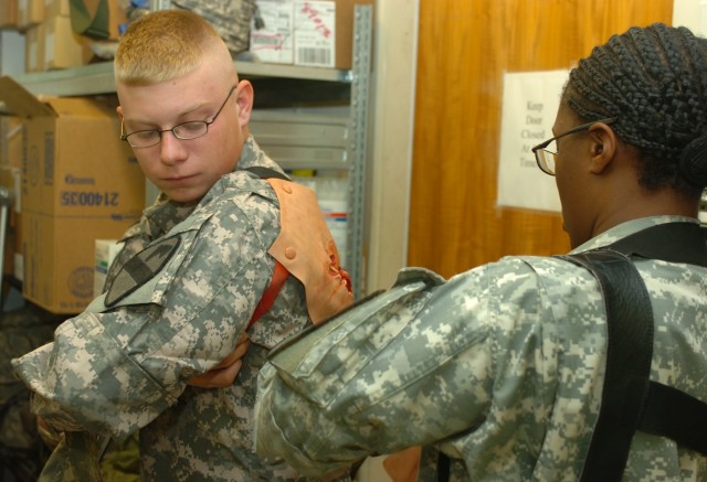 CAMP LIBERTY, Iraq - Prior to a mass casualty exercise on Camp Liberty, Ripley, Tenn. native, Capt. Marolyn Pearson (right), division senior physician assistant, Division Special Troops Battalion, 1st Cavalry Division, assists Windsor, Calif....