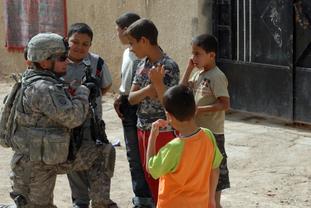 BAGHDAD - Sgt. 1st Class Eric 'Smoke' Austin, the 3rd Platoon sergeant assigned to B Battery, talks with local children during a patrol in the Karrada district of southeastern Baghdad, March 28. Austin, a native of Lawton, Okla., explained, "We...