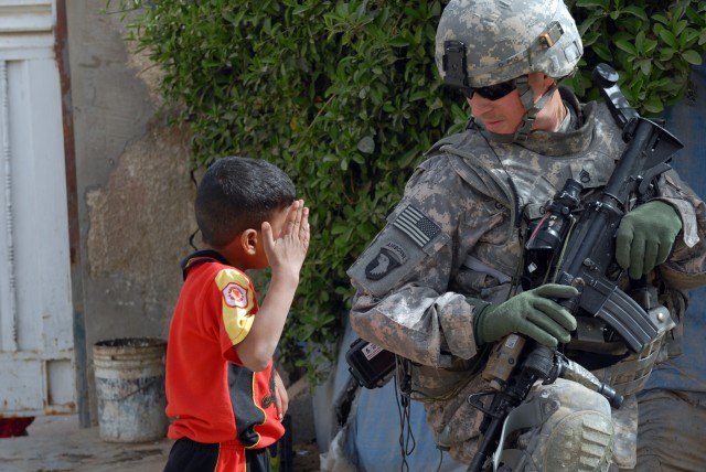 BAGHDAD - An Iraqi children salutes Staff Sgt. Michael Graham, a squad leader assigned to 3rd Platoon, B Battery, while he takes a rest during a patrol in the Karrada district of southeastern Baghdad, March 28. "There's pretty much not a patrol...
