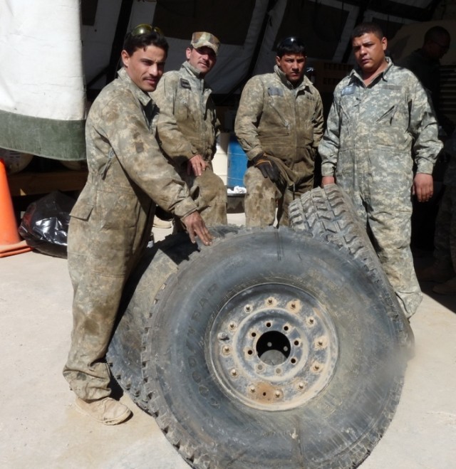 CAMP LIBERTY, Iraq - Spc. Mouafaq (far left), Spc. Yasir, Spc. Mouafaq, and Spc. Zydoun (far right), mechanics with the 6th Iraqi Army Division, pose in front of tires they are about to install during their joint vehicle maintenance training...