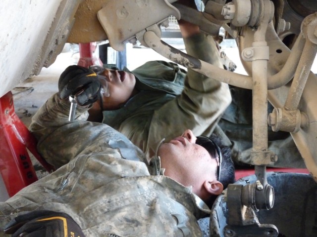 CAMP LIBERTY, Iraq - Fredricksburg, Va. native Spc. Melvin Lawson (top of photo), all-wheel vehicle mechanic, Company B, 46th Engineer Combat Battalion (Heavy) shows Spc. Malik, 6th Iraqi Army Division, mechanic, how to install a new radiator hose...