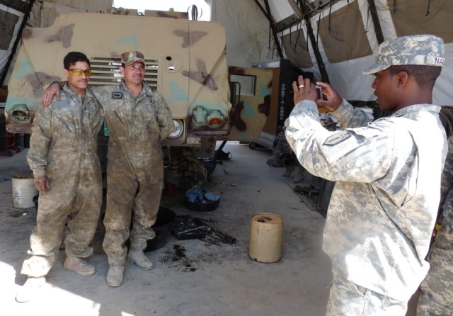 CAMP LIBERTY, Iraq - Sgt. 1st Class Cornelius Nalls (right), motor sergeant, Company B, 46th Engineer Combat Battalion (Heavy), and a native of Fayette, Ala., snaps a photo of Spc. Mouafaq and Spc. Yasir, mechanics with the 6th Iraqi Army...