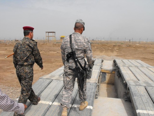 TAJI, Iraq - Brig. Gen. Owen Monconduit (right), 225th Engineer Brigade commander and Iraqi Army Col. Flahe, commander of the Taji engineer school, walk over a portable bridge that IA Soldiers placed over a concrete wash rack. Flahe said Soldiers are...