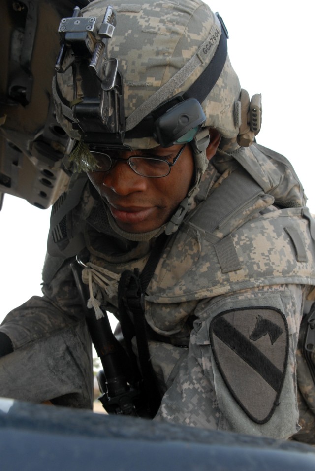 BAGHDAD - Chicago native, Pfc. Gbenga Ayantade, a combat medic assigned to the 1st Battalion, 5th Cavalry Regiment checks vehicles for improvised explosive device materials, unregistered weapons and anything else illegal during an operation April...