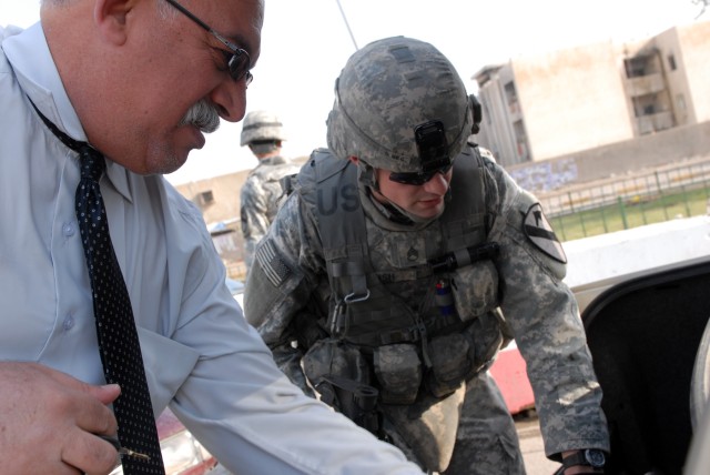 BAGHDAD - Staff Sgt. Gerald Bush, an infantry squad leader from Holly Hill, S.C., assigned to the 1st Battalion, 5th Cavalry Regiment, checks the back of an Iraqi man's trunk an operation April 9 here. "The whole entire city is a checkpoint...
