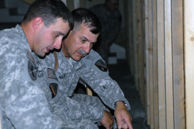 BAGHDAD - Ventress, La. native, Command Sgt. Maj. Joe Major (right), senior enlisted leader, 225th Engineer Brigade, discusses the anchoring and floor support system that is being constructed at Joint Security Station War Eagle by Staff Sgt. Ryan...