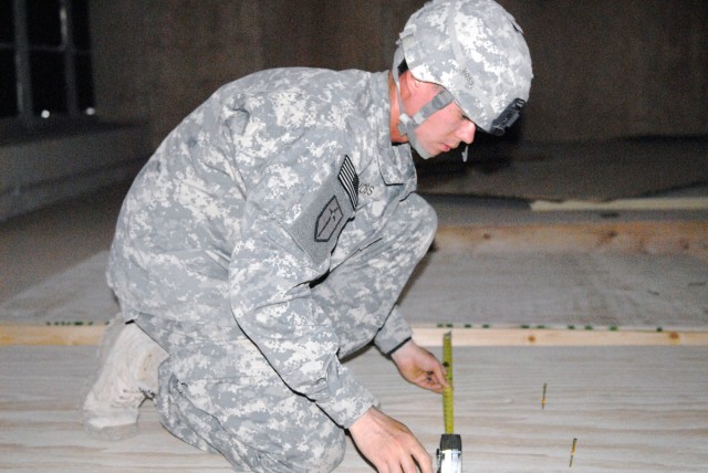 BAGHDAD - Minneapolis native, Spc. Samuel Voss, marks studs while attaching plywood sheathing to a wall section during construction at Joint Security Station War Eagle, April 13. Samuel, along with his fellow Soldiers from the 46th Engineer...