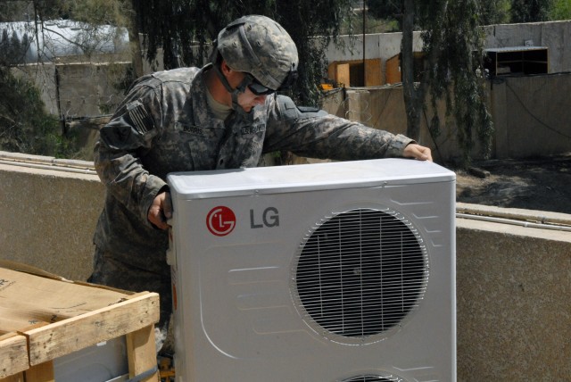 BAGHDAD - Kanapolis, N.C. native, Spc. Kyle Burris, 46th Engineer Battalion, 225th Eng. Brigade, moves an air conditioning unit into place so he can wire it for use at Joint Security Station War Eagle, April 13. Kyle, along with his fellow...