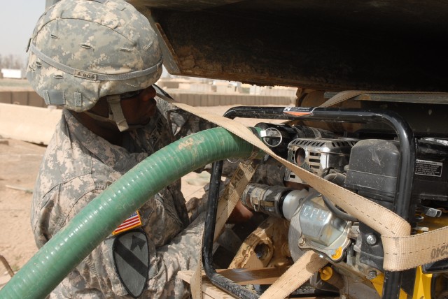 Spc. Gregory Williams, a Shreveport, La. native, and a water purification specialist for Company A, 15th Brigade Support Battalion, 2nd Brigade Combat Team, 1st Cavalry Division, attaches a hose to a water pump March 30. He is one of the "Waterdogs" ...