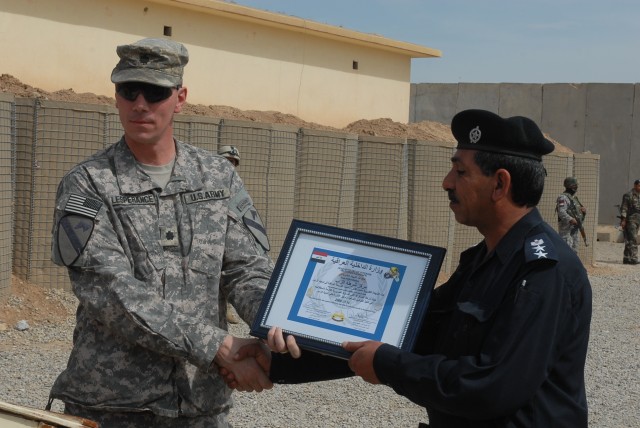 Lt. Col. David Lesperance, the commander of 1st Battalion, 8th Cavalry Regiment, 2nd Brigade Combat Team, 1st Cavalry Division, gives a certificate to Col. Muhammad Mohsin, the Zaab police chief, during a validation ceremony held in Hawijah, Iraq,...